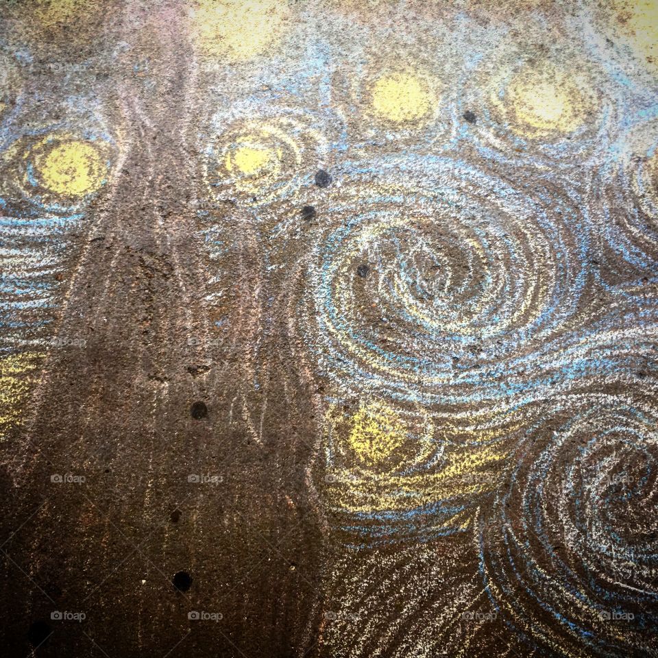 Sidewalk chalk art on an urban sidewalk depicting the Van Gogh masterpiece The Starry Night.
