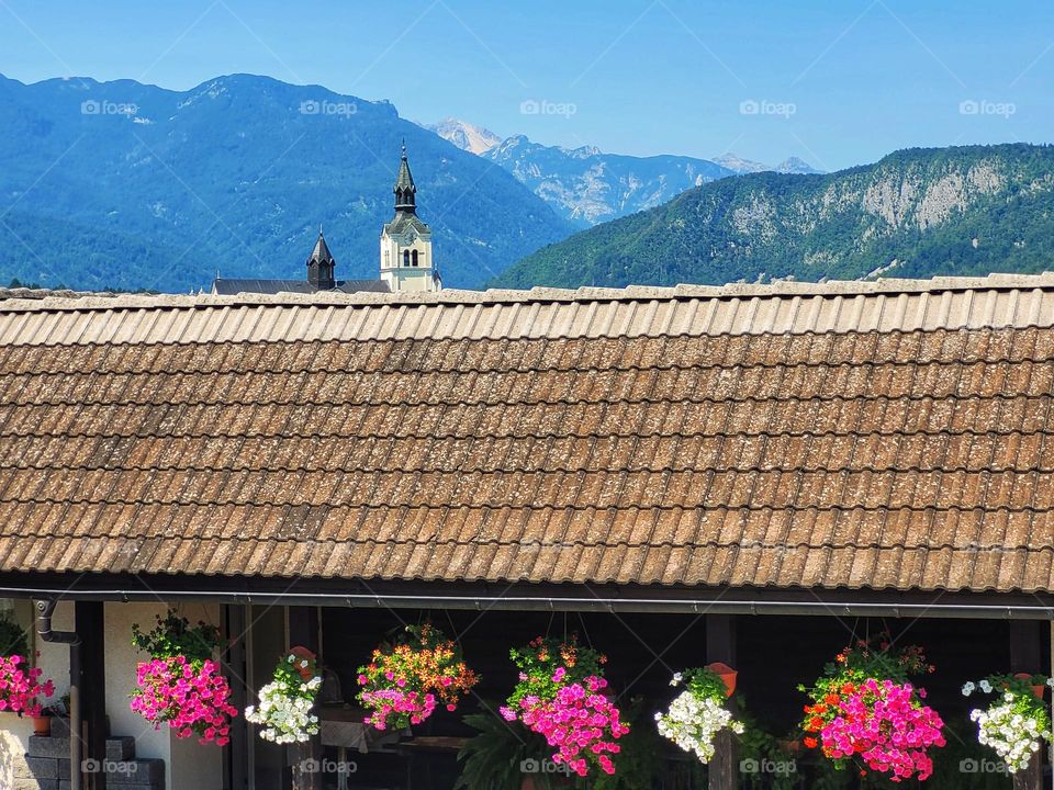 The roof of cozy house with flowers against blue sky in summer village.