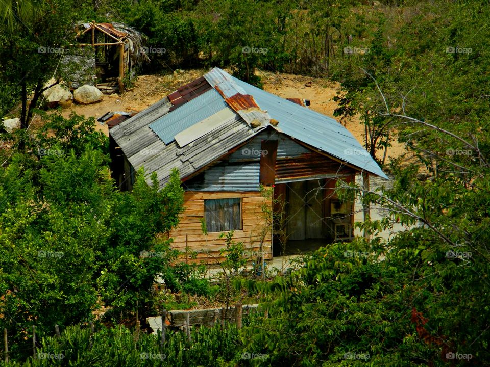 Rural vs Urban living - Urban areas are large areas that consists of both living and working areas with high population. A house with a tin roof is surrounded by undeveloped land. People live on the basic necessities. 