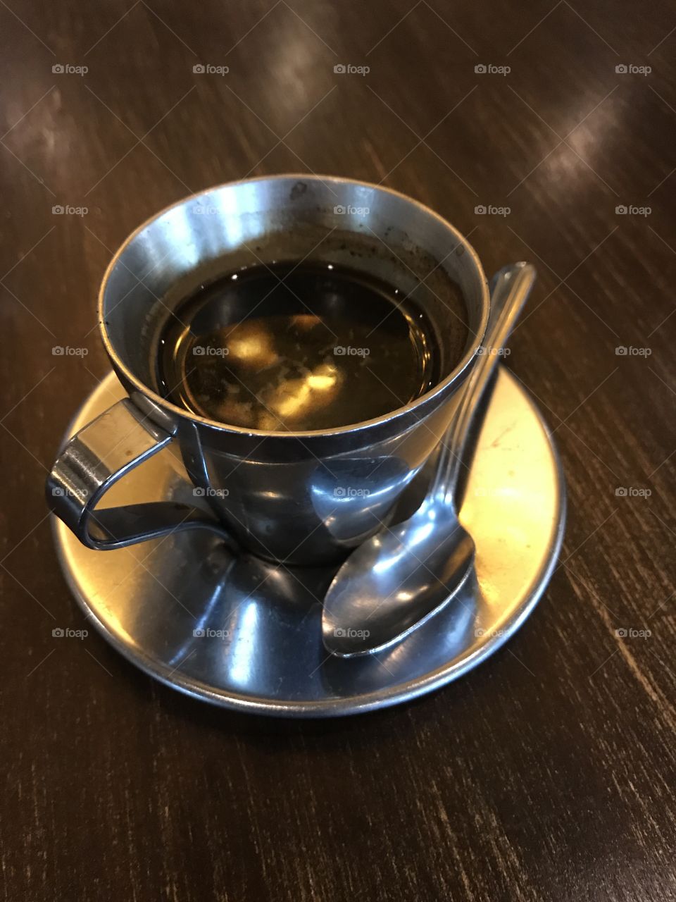 Small Cuban coffee espresso drink in a metal cup with a metal saucer can tiny spoon for sugar