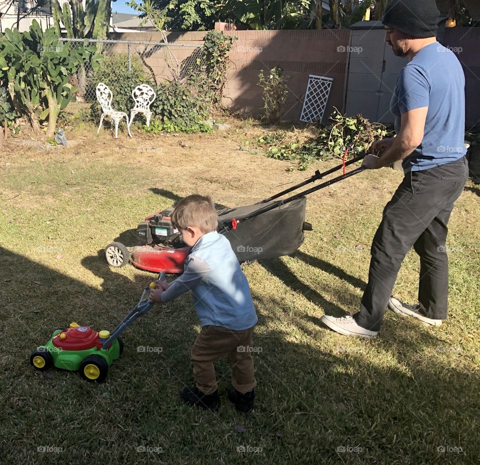 Father and child pretend to mow the lawn