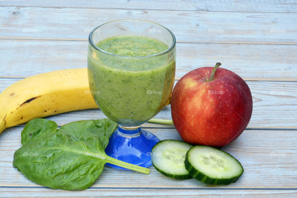 Green smoothie with spinach,apple,banana and cucumber on a wooden table background