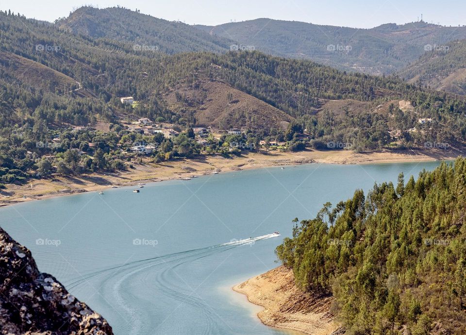 Follow the wake of a powerboat along the mountainous countryside along the Rio Zêzere, Central Portugal 