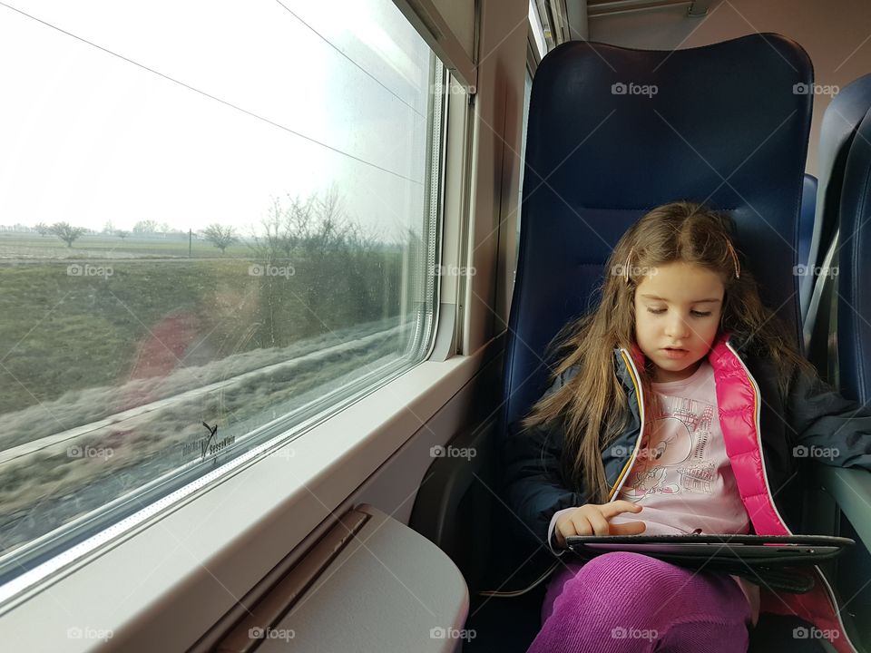 Travelling girl on train playing with mobile