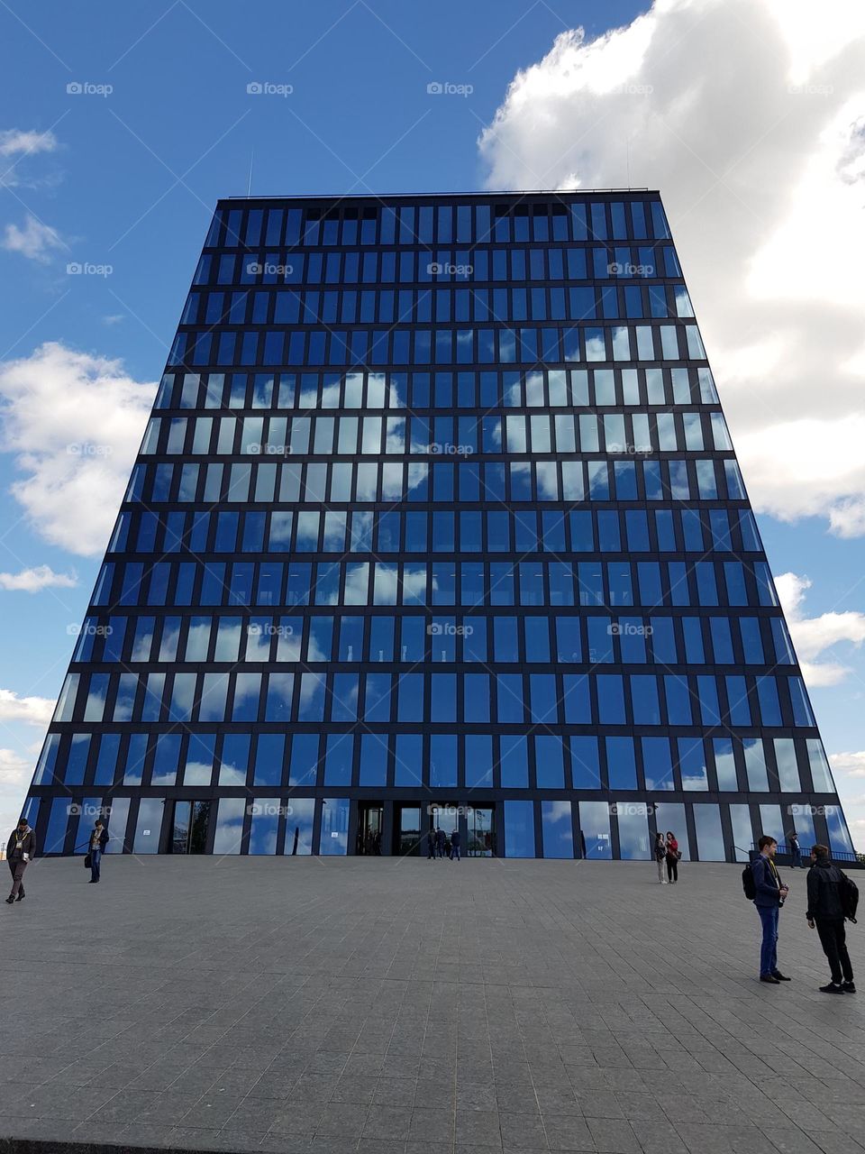 Clouds in blue sky are reflected in the glass facade of a building with modern architecture (no filter, no photoshop)