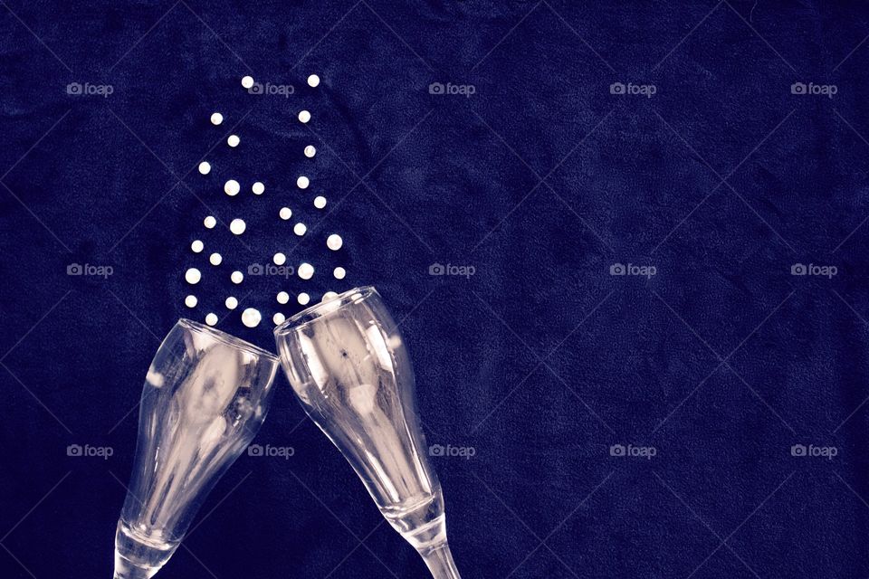 Flat lay of champagne glasses with rhinestone bubbles on classic blue background