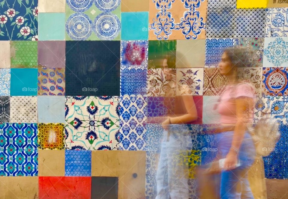 Two girls in front of a colorful wall