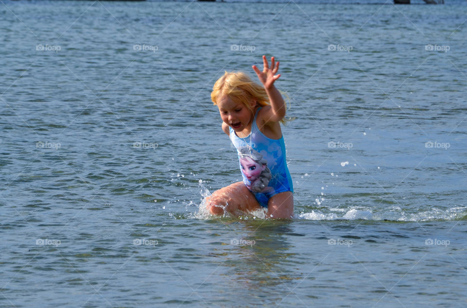 Young girl is running in the water at Ribban in Malmö Sweden.