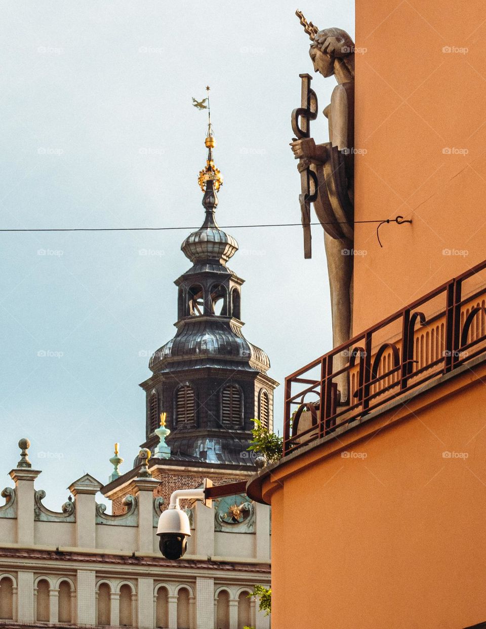 a beautiful figure on the corner of a tenement house in the background a fragment of the town hall tower and the cloth hall on the market square in krakow