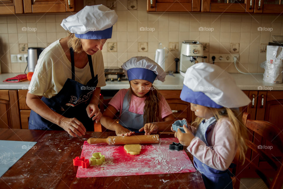 Little sisters with grandma cooking the biscuits 