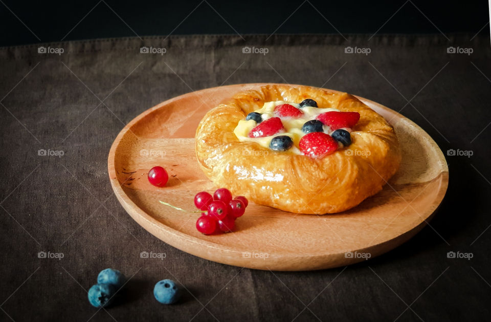 Homemade cakes with berries on a dark background.  Appetizing fresh denish with cream, strawberries, blueberries and currants on a wooden tray.  Autumn mood