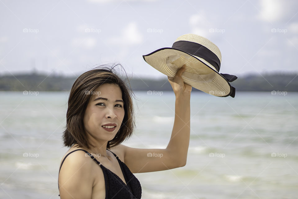 Portrait of Asian woman wearing a swimsuit background sea and sky