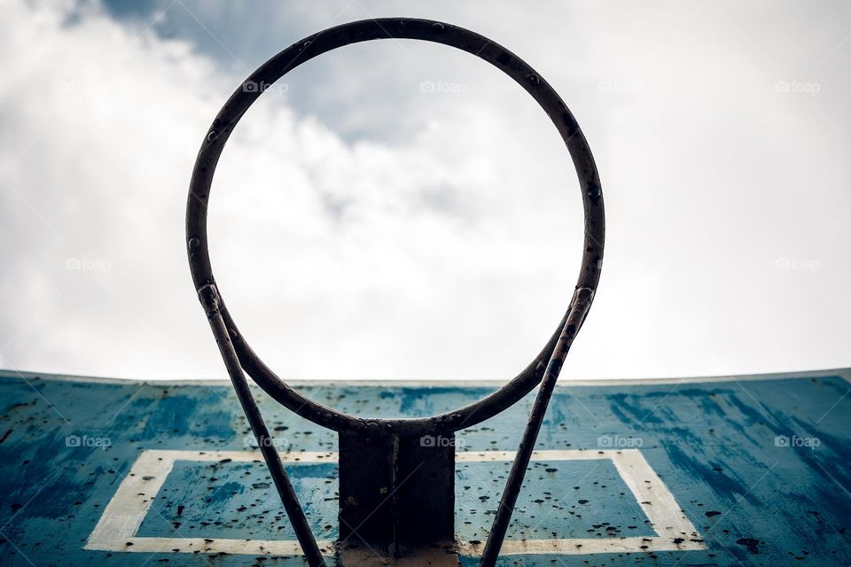 Bottom view of basketball hoop against cloudy sky