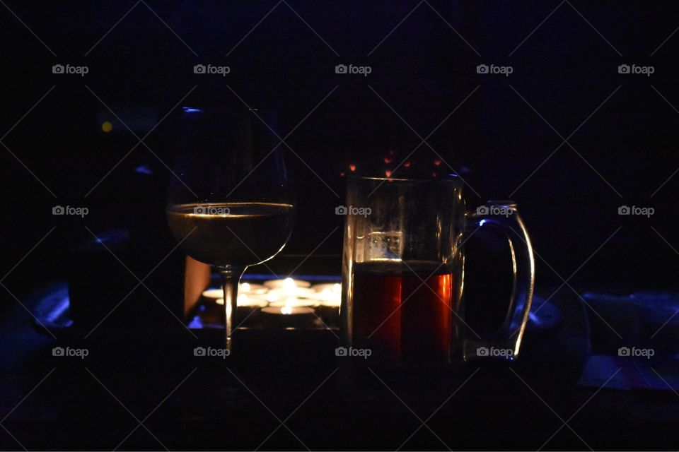 Glass of wine and mug of beer by candlelight 