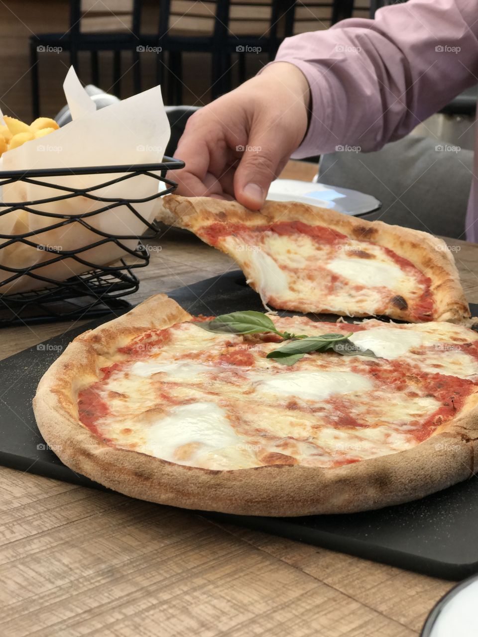 Fresh Italian pizza on a wood table. Delicious Pizza Margherita. Taking a slice of pizza 