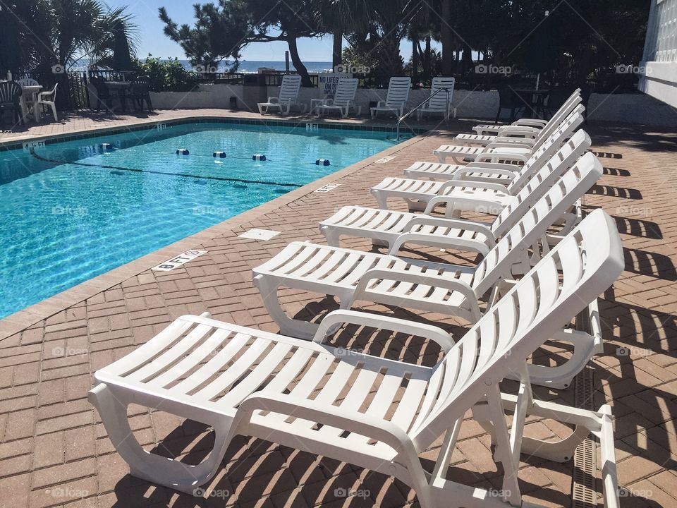 A resort swimming pool with white chaise lounges.