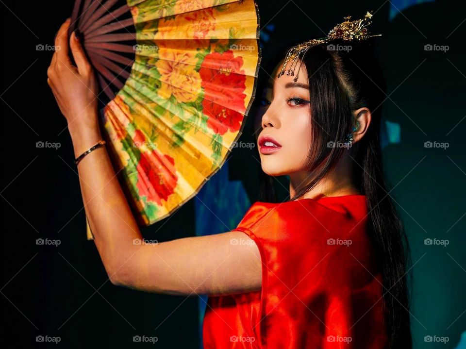 Portrait of young woman in traditional dress holding a large fan