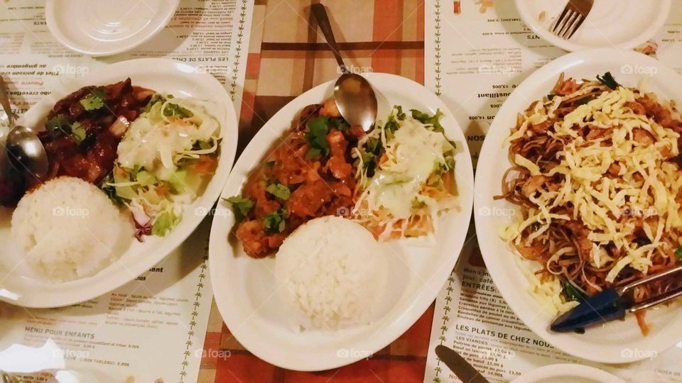 3 different mauritius meals in a restaurant with meat, rice, salad and spicy sauce