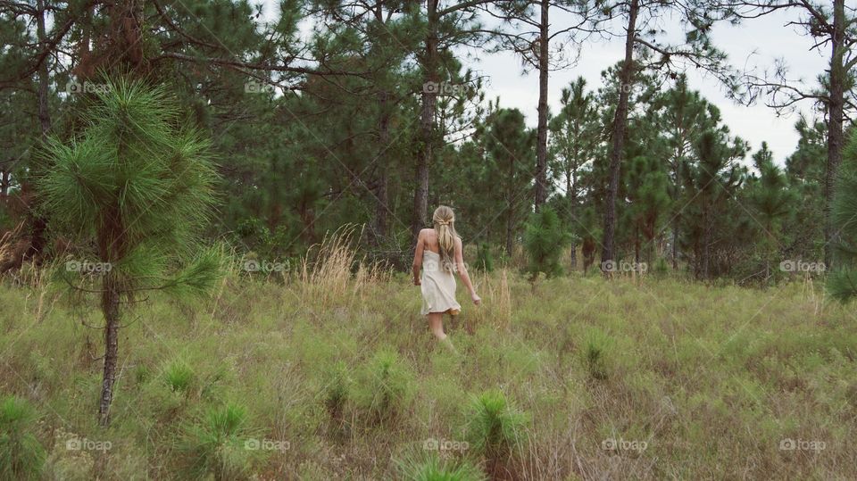 Beautiful blonde young girl walking un the woods