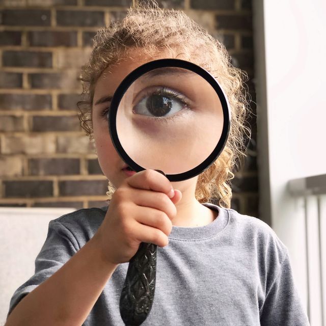 Child looking through a magnifying glass with one eye 