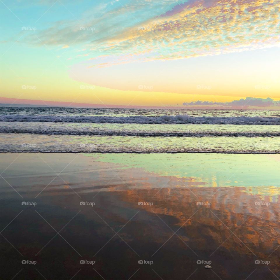 Sunrise on the beach pinks and greens sand sea