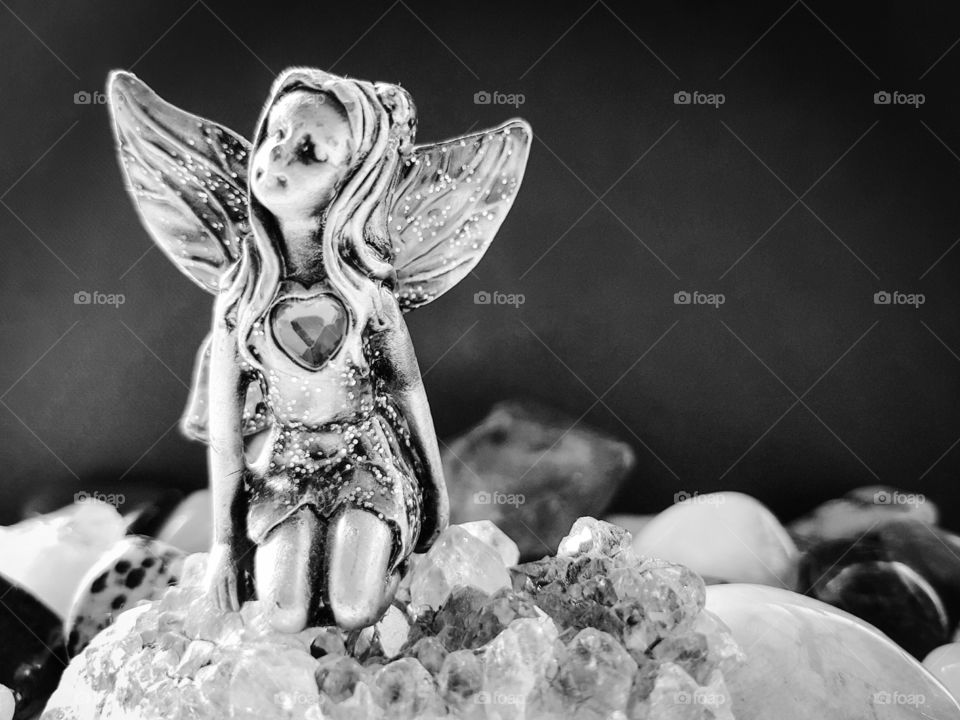 Black And White photo, Fairy Sitting on Amethyst surrounded by gem stones.
