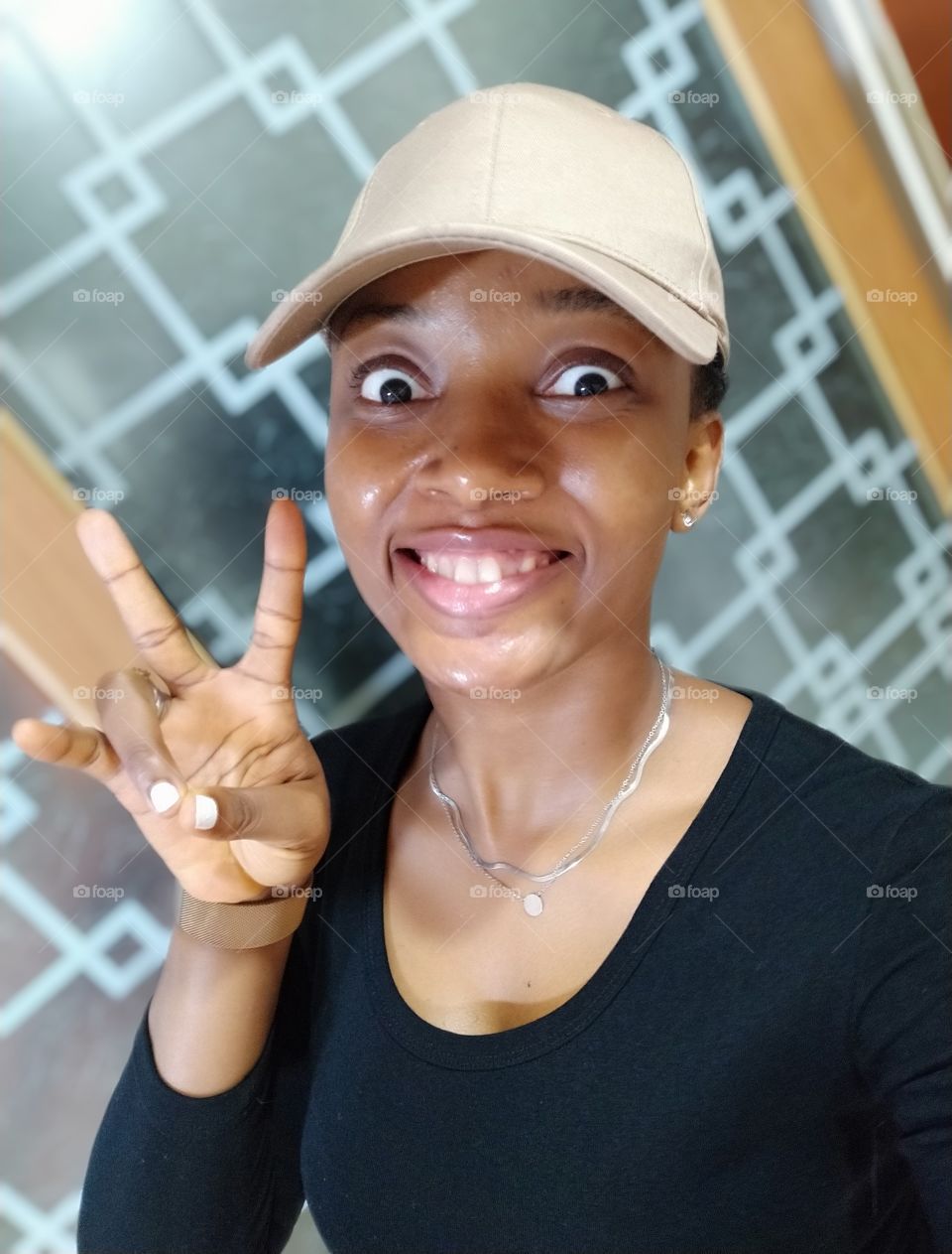 Lady putting on a face cap and smiling with bulging eyes. Two fingers up