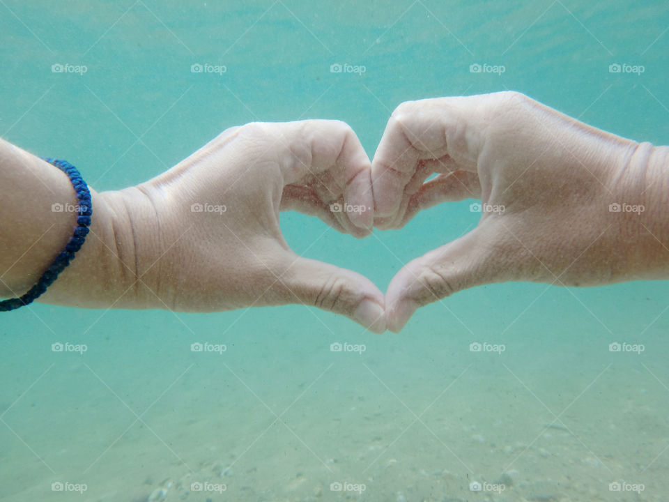 heart shape underwater. heart shape of hands underwater