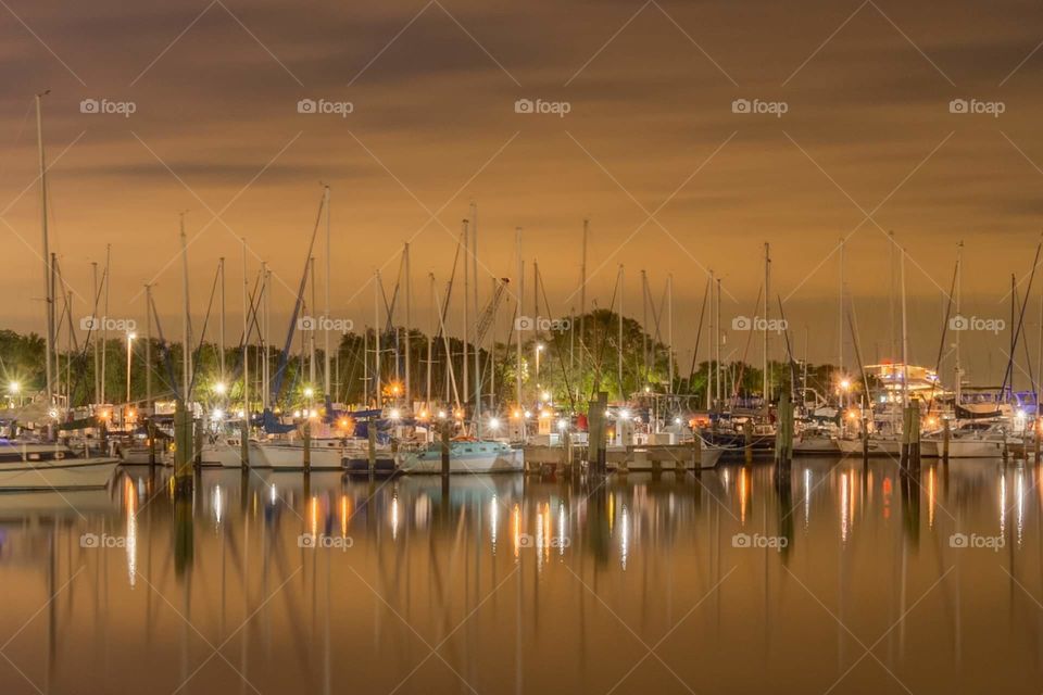 a beautiful sunset over a small boat marina  with reflections in the water of the bay