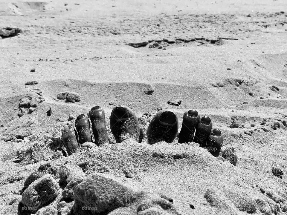 Feet under the sand in black and white 