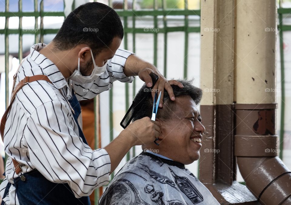 A man enjoy while open air haircutting