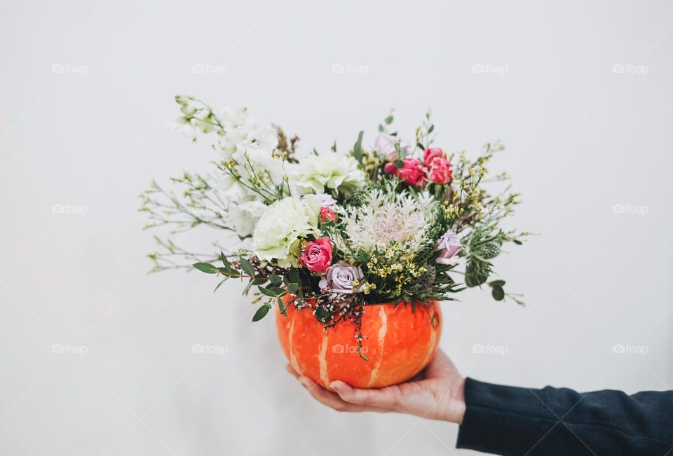 DIY autumn flower arrangement bouquet in pumpkin, florist at work, floristry studio