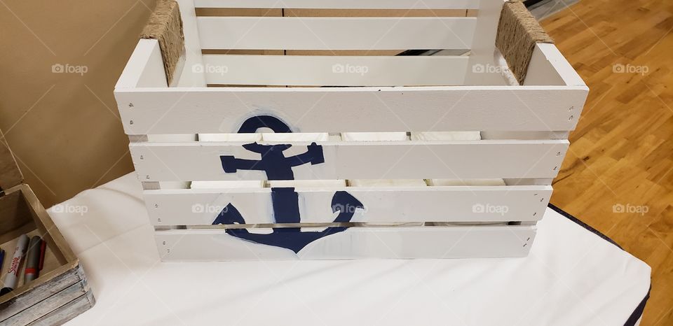 Crate I purchased, painted white, stenciled an anchor, and wrapped the handles in twine.. for a nautical themed baby shower.