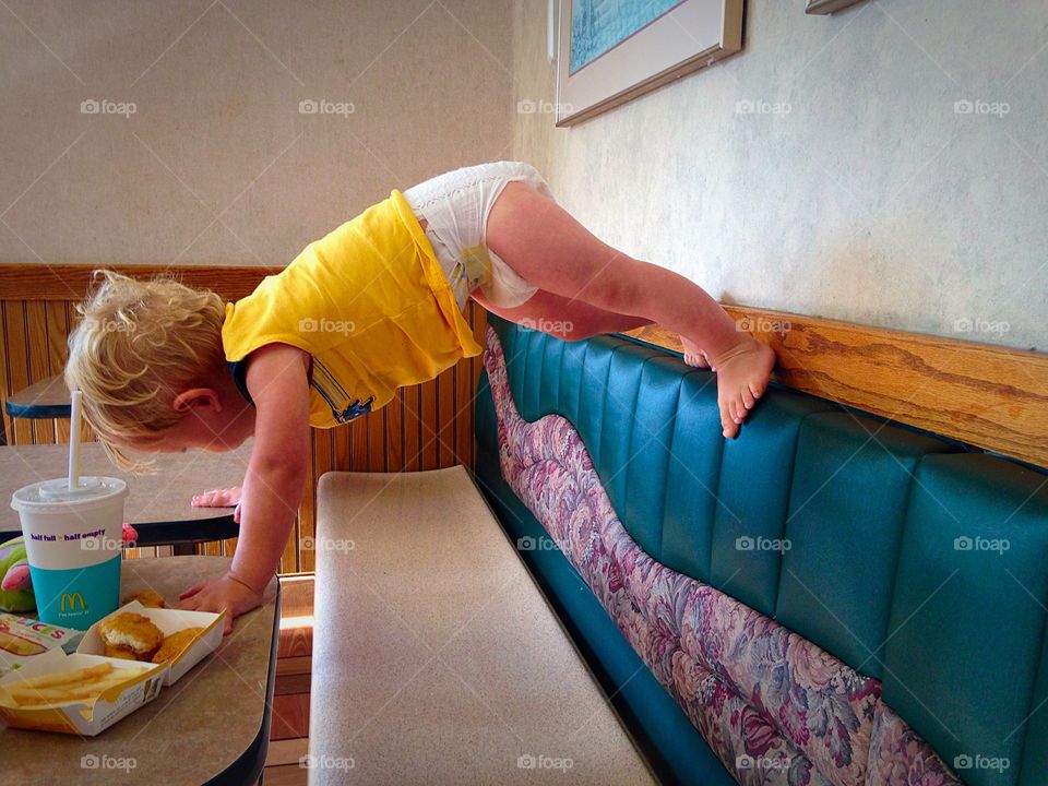 Climbing the Walls. Energetic toddler boy climbing the wall during dinner at McDonalds.