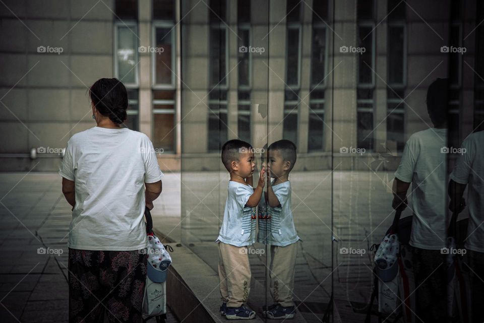 A kid seeing himself in the glass wall