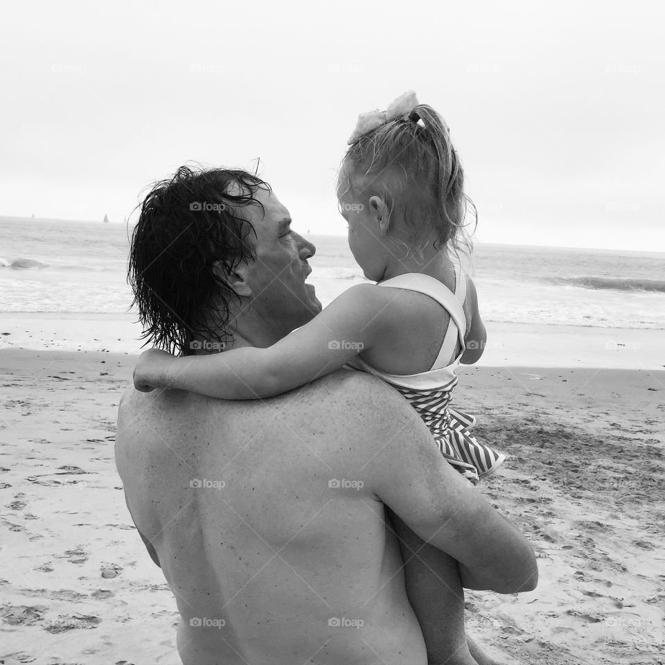 Father holding daughter at beach