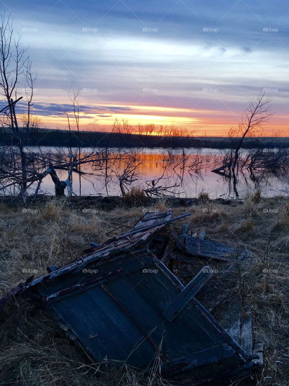 Ruins of boat near lake at sunset