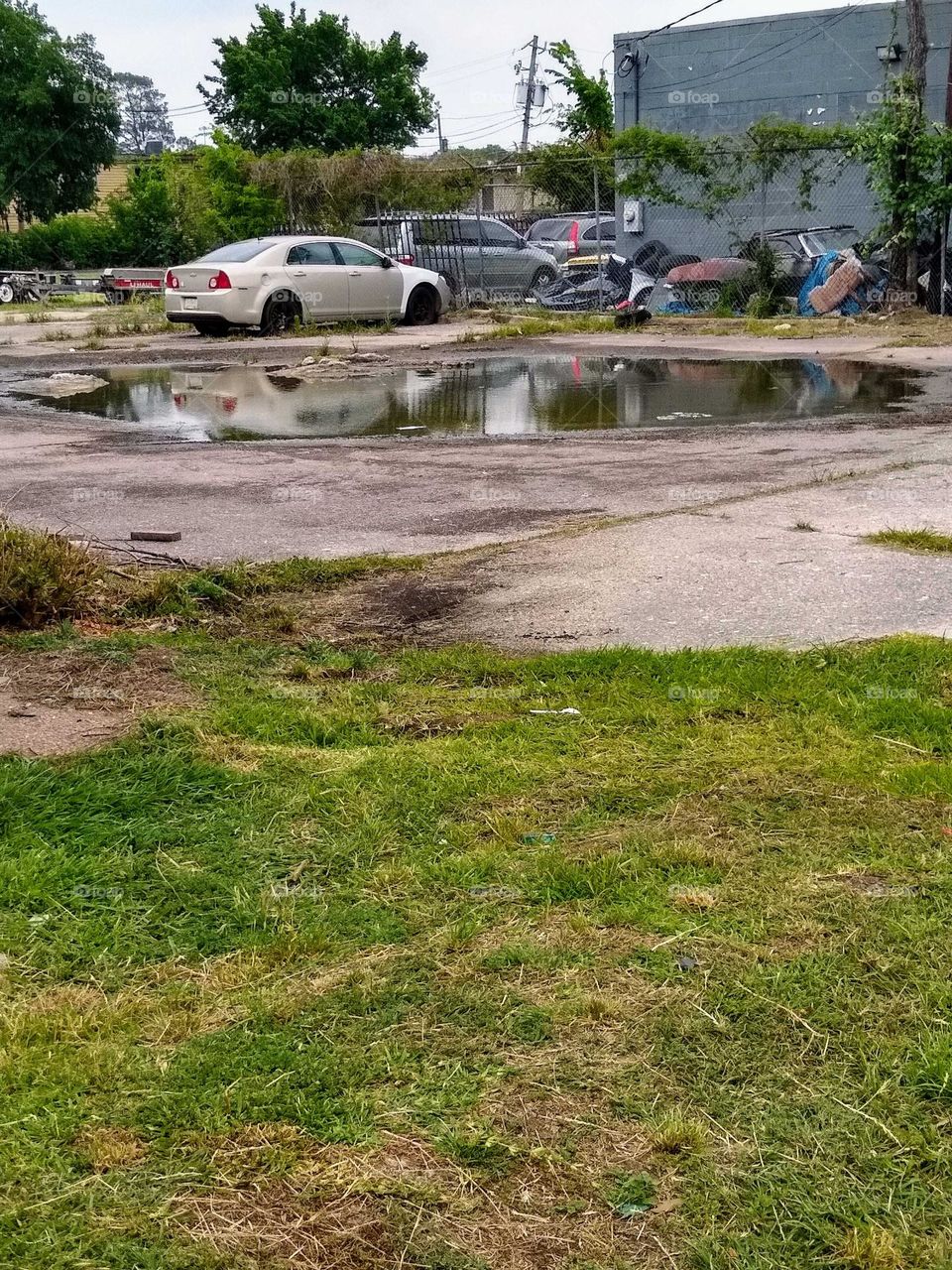A large puddle of water 💦 near a car 🚗 shop. There after a recent rain shower🌧️.