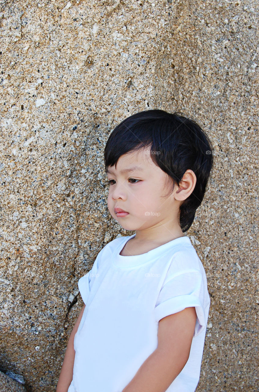 Portrait Asian boy are smiling the background stones , Koh Lipe at Satun in Thailand.