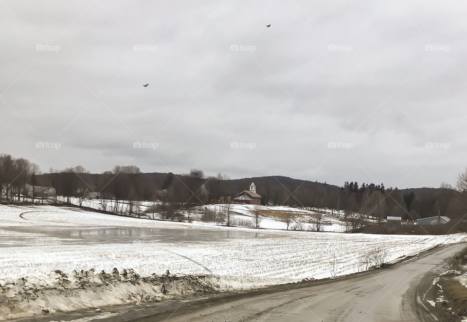 Road into town - rural town in Vermont.  Straight ahead is the church in town, beyond the snow covered field. 