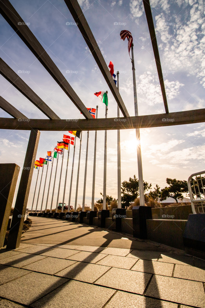 Flags of all nations flying high at a beautiful memorial, as the setting sun sheds golden light on the scene.