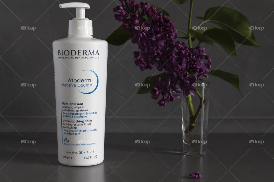 Skin cream on a gray background with purple lilac.