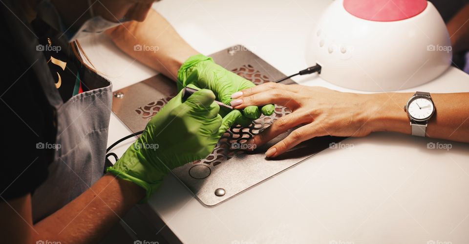 Nail salon. A young woman does a colored manicure.The manicurist covers her nails with nail Polish. A woman does a manicure and applies nail Polish