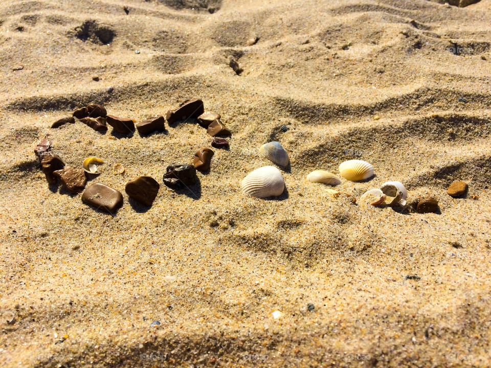 Love heart made with stones and shells on a sand