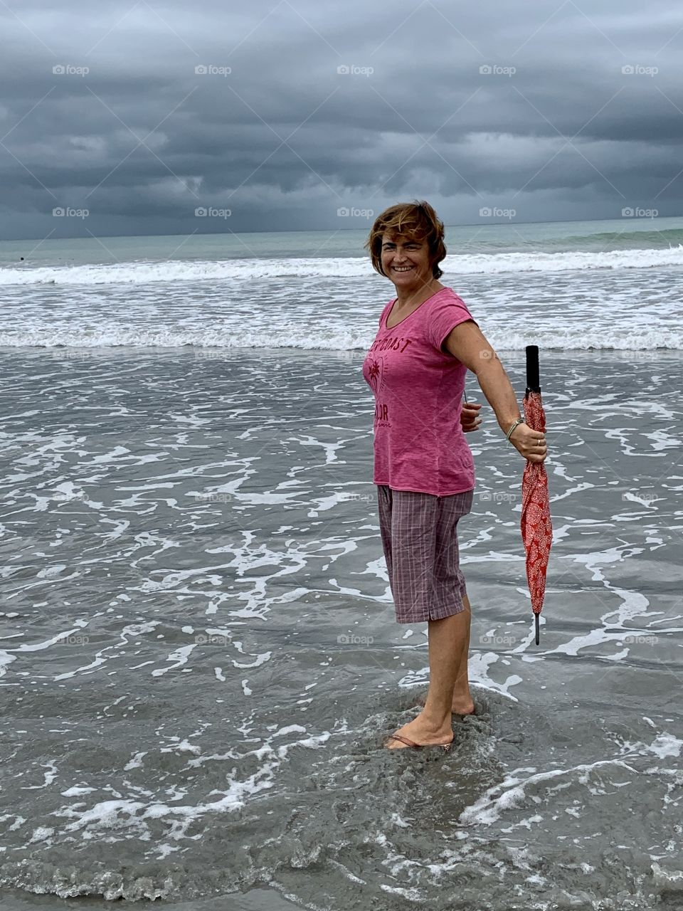 Woman in the beach in a raining day with umbrella 