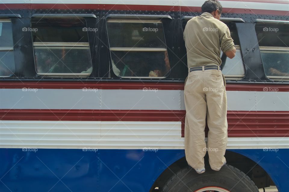 Rear view of a man standing on bus tier