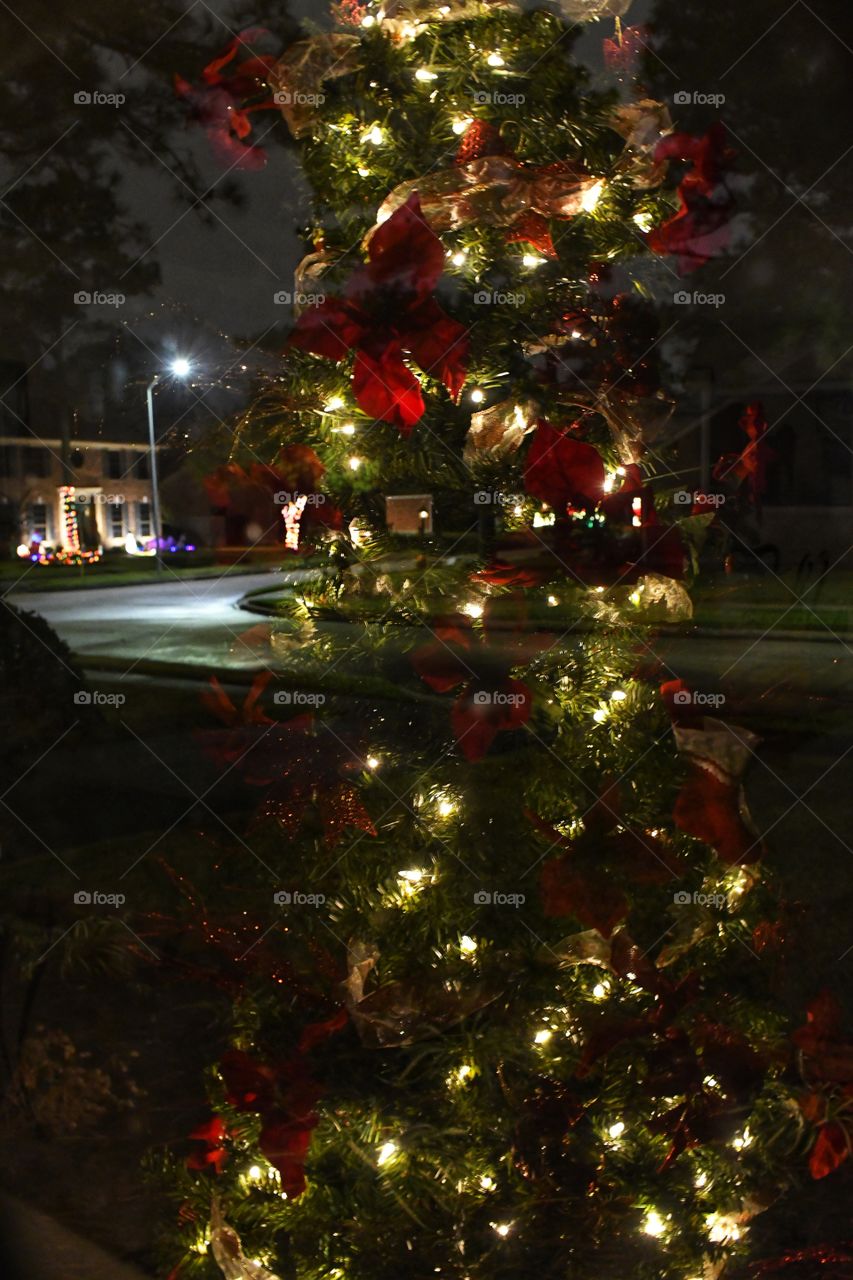 A reflection of a lighted Christmas tree on the window