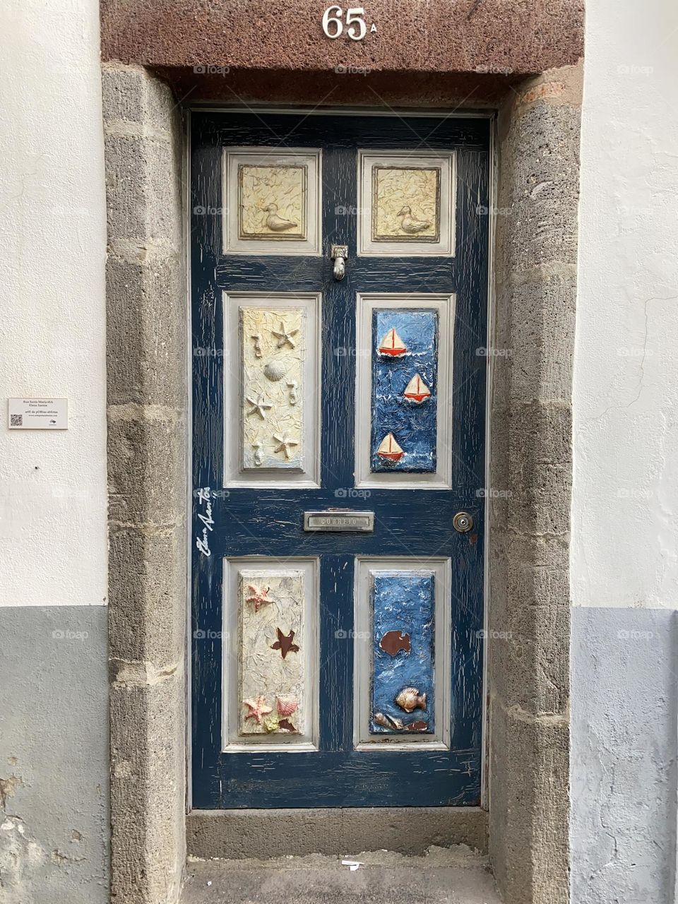 A dark blue painted door with six panels depicting the underwater world of starfish and fish in old town Funchal 