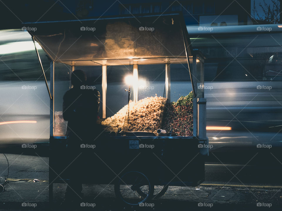 The silhouette of a guy selling popcorn on the street