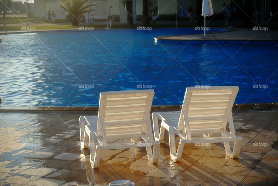Last day on vacation. Two lounge chairs by the pool at sunset.